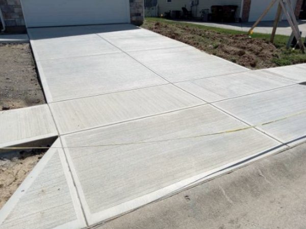 Newly poured driveway with fresh saw-cut joints where it meets the sidewalk